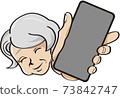 An elderly woman holding her smartphone over here 73842747