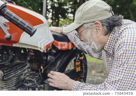 Bike life Senior rider maintaining a bike Bike life Senior rider maintaining a bike 73843459