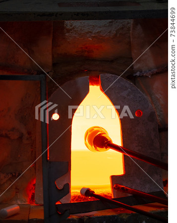 Glassblower keep the glassblowing pipe in gass furnace stove. 73844699