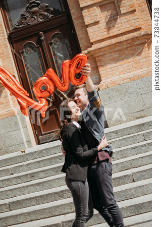 Couple in love. Valentines day celebration, love and dating outdoor concept. Happy loving couple walking on the city street, hugging and kissing 73844738