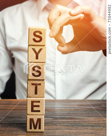Men knocks down wooden block tower with word System. System destruction concept. The threat of violation of integrity, violation. Sabotage. Resistance. Political change of power. Social revolution 73844982