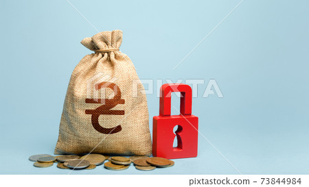 Ukrainian hryvnia money bag and red padlock. Tight government control over the financial system. Cash flow monitoring. Freezing of pension savings. Blocking bank accounts and seizing assets. Ukrainian hryvnia money bag and red padlock. Tight government control over the financial system. Cash flow monitoring. Freezing of pension savings. Blocking bank accounts and seizing assets. 73844984