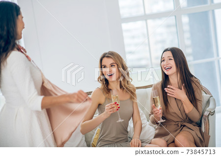 Three beautiful girls choosing a dress and looking excited 73845713