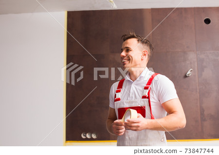 The smiling builder is going to glue a protective tape 73847744