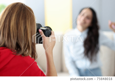Woman photographer photographs model on couch closeup 73848018
