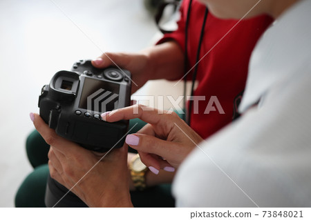 Two women hold camera in their hands Two women hold camera in their hands 73848021
