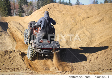 The back of a quader going up a gravel hill 73848891