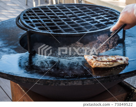 Cook prepares ribs on a circular grill Cook prepares ribs on a circular grill 73849522