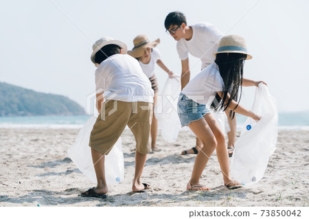 Asian Family volunteer picking up a plastic bottle on a beach with a sea to protect an environment 73850042