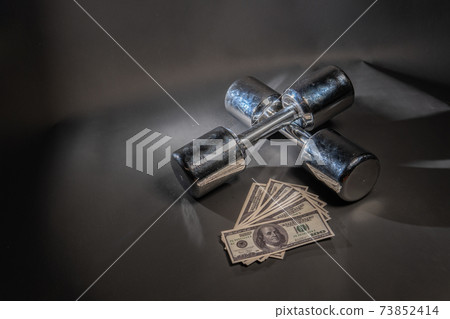 Dumbbells athletics lie, money dollars glitter on a black background Dumbbells athletics lie, money dollars glitter on a black background 73852414