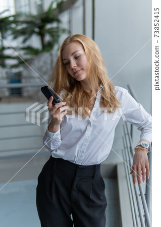 woman talking on the phone. Joyful with a lovely smile, wellbeing concept, on against the window, by the railing woman talking on the phone. Joyful with a lovely smile, wellbeing concept, on against the window, by the railing 73852415
