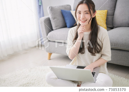 Young woman using a computer in the living room Young woman using a computer in the living room 73853370