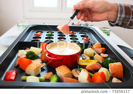 Family dining table with ajillo and cheese fondue on a hot plate Family dining table with ajillo and cheese fondue on a hot plate 73856157