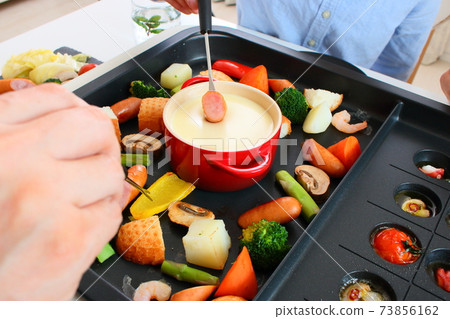 Family dining table with ajillo and cheese fondue on a hot plate 73856162