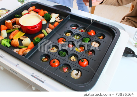 Family dining table with ajillo and cheese fondue on a hot plate Family dining table with ajillo and cheese fondue on a hot plate 73856164