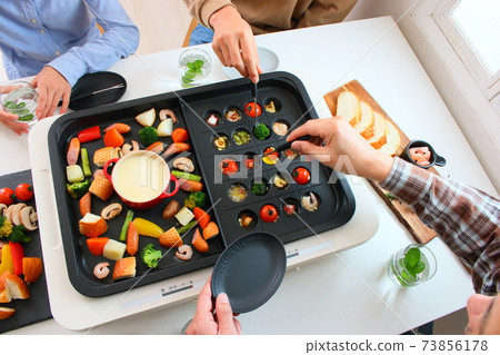 Family dining table with ajillo and cheese fondue on a hot plate 73856178