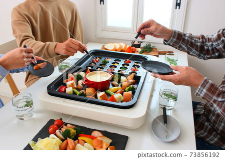 Family dining table with ajillo and cheese fondue on a hot plate Family dining table with ajillo and cheese fondue on a hot plate 73856192