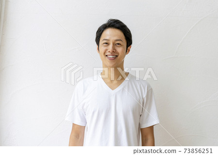 A man in his thirties smiling looking at the camera in a white T-shirt 73856251