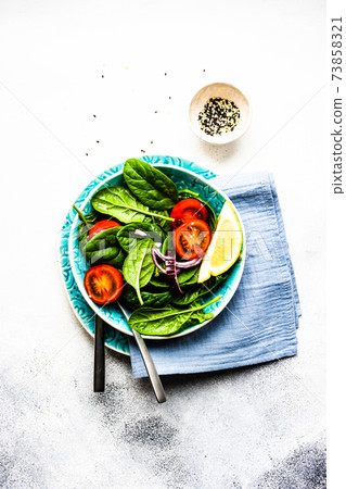 Healthy food salad with fresh organic spinach leaves with sesame seeds served in a bowl on concrete background with copy space Healthy food salad with fresh organic spinach leaves with sesame seeds served in a bowl on concrete background with copy space 73858321