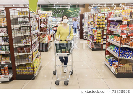 Young female customer in a mask shopping at a supermarket Young female customer in a mask shopping at a supermarket 73858998