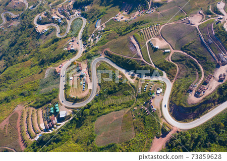 Aerial view of cars driving on curved, zigzag curve road or street on mountain hill with green natural forest trees in rural area of Phu Tub Berk, Phetchabun, Thailand. Aerial view of cars driving on curved, zigzag curve road or street on mountain hill with green natural forest trees in rural area of Phu Tub Berk, Phetchabun, Thailand. 73859628