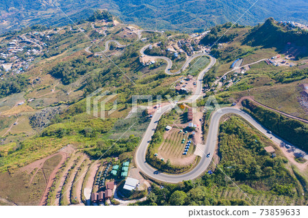 Aerial view of cars driving on curved, zigzag curve road or street on mountain hill with green natural forest trees in rural area of Phu Tub Berk, Phetchabun, Thailand. Aerial view of cars driving on curved, zigzag curve road or street on mountain hill with green natural forest trees in rural area of Phu Tub Berk, Phetchabun, Thailand. 73859633