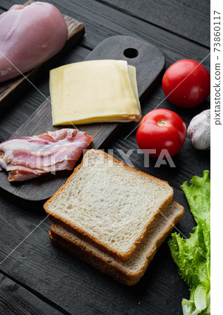 Ingredient for sandwich, bacon, cheese, tomato, chicken meat, lettuce, sauce, on black wooden table Ingredient for sandwich, bacon, cheese, tomato, chicken meat, lettuce, sauce, on black wooden table 73860117