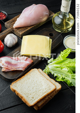 Ingredient for sandwich, bacon, cheese, tomato, chicken meat, lettuce, sauce, on black wooden background Ingredient for sandwich, bacon, cheese, tomato, chicken meat, lettuce, sauce, on black wooden background 73860132