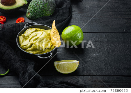 Nachos corn tortilla chip with avocado dip or guacamole, on black wooden background with copy space for text 73860653