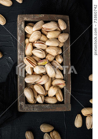 Shelled unsalted pistachios, on black textured background, flat lay 73860742