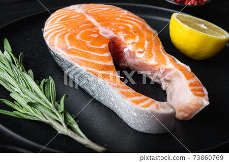 Salmon steak raw fish with herbs, on black wooden surface Salmon steak raw fish with herbs, on black wooden surface 73860769