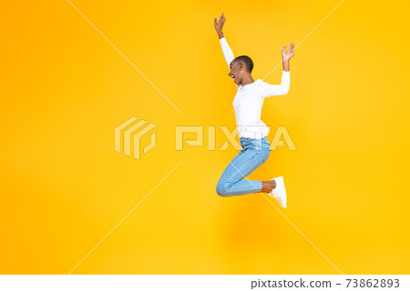 Happy excited African American woman jumping with hands raising Happy excited African American woman jumping with hands raising 73862893
