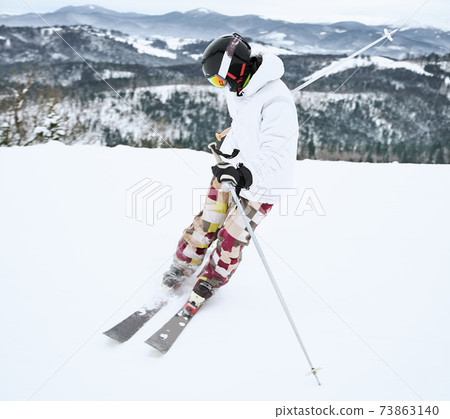 Skier wearing ski equipment spending time on mountain slopes in winter season 73863140