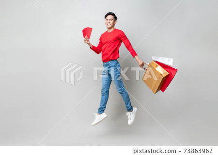 Surprised Asian man holding bags and red envelope or Ang Pao jumping 73863962