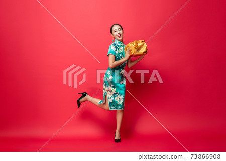 Happy smiling Asian woman in traditional costume holding gold gift box in red Happy smiling Asian woman in traditional costume holding gold gift box in red 73866908