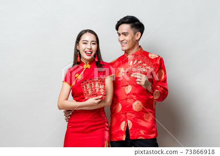 Happy Asian couple in oriental costumes holding red envelopes or Ang Pao Happy Asian couple in oriental costumes holding red envelopes or Ang Pao 73866918
