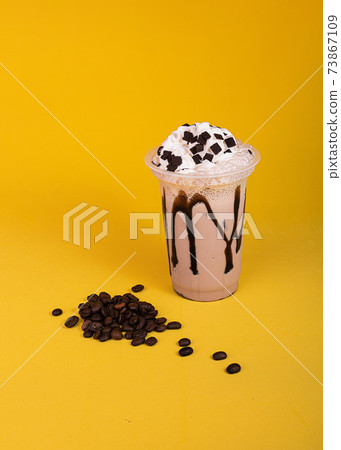 Milkshake with coffee topping. Iced chocolate with whipped cream on a yellow background. 73867109