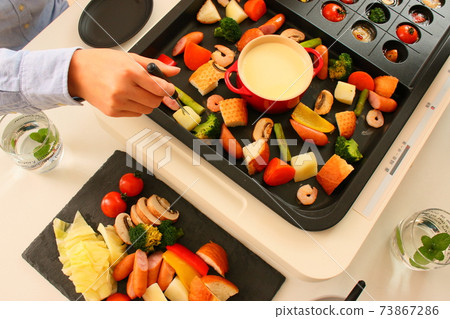 Family dinner with ajillo and cheese fondue on a hot plate 73867286