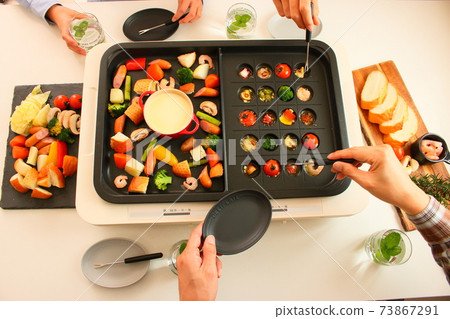 Family dinner with ajillo and cheese fondue on a hot plate 73867291