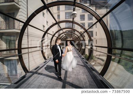 Happy just married couple walking beautiful round window in wedding day Happy just married couple walking beautiful round window in wedding day 73867500