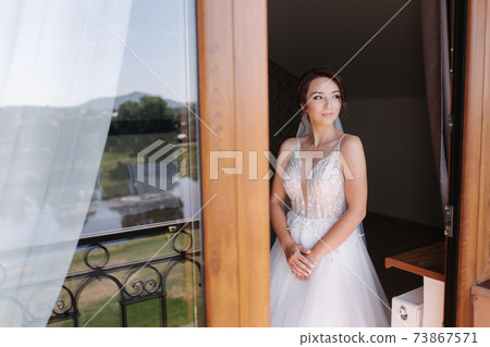 Portrait of elegant bride in fashion wedding dress stand on the balcony and posing to photographer 73867571
