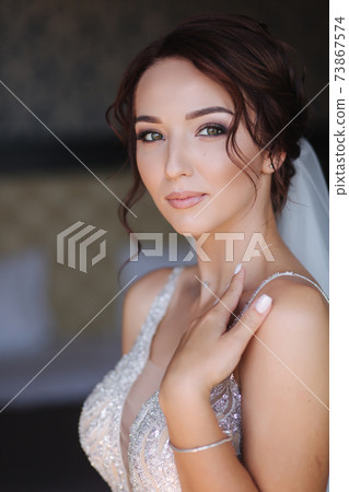 Portrait of elegant bride in fashion wedding dress stand on the balcony and posing to photographer Portrait of elegant bride in fashion wedding dress stand on the balcony and posing to photographer 73867574