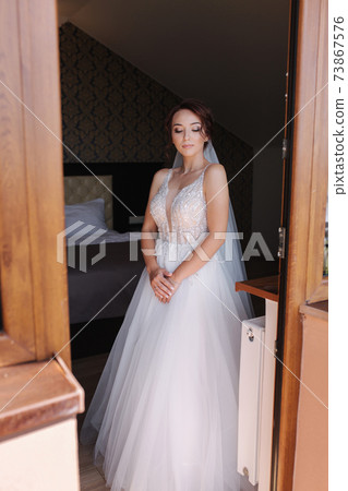 Portrait of elegant bride in fashion wedding dress stand on the balcony and posing to photographer Portrait of elegant bride in fashion wedding dress stand on the balcony and posing to photographer 73867576