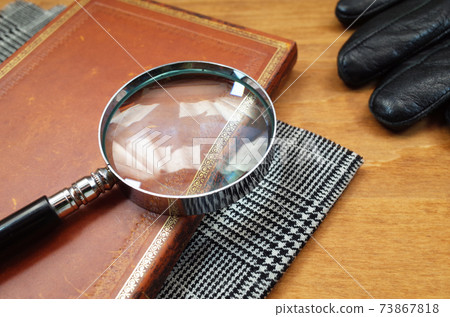 Detective scene with magnifying glass, notebook, plaid and gloves 73867818