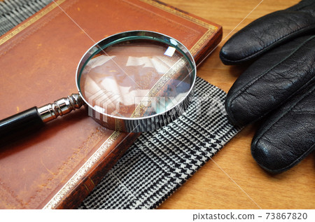Detective scene with magnifying glass, notebook, plaid and gloves 73867820