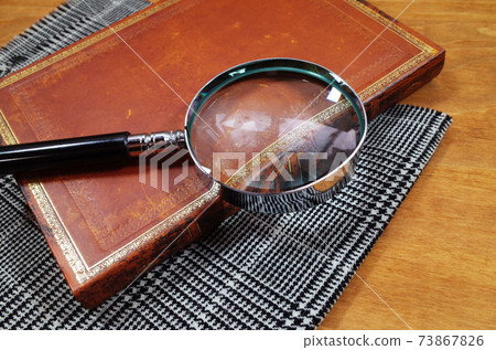 From the left, a magnifying glass, a notebook, and a plaid detective scene 73867826