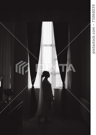 Silhouette of bride open curtains in hotel. Big window 73868039
