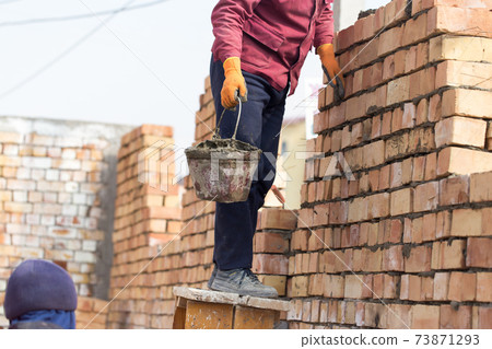 Worker builds a brick wall in the house 73871293