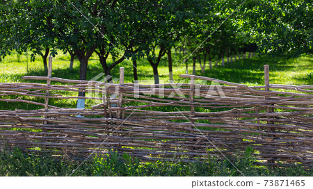 Fence of wooden branches in the garden Fence of wooden branches in the garden 73871465