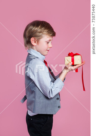Valentines day. Charming little boy with gift box on pink studio background Valentines day. Charming little boy with gift box on pink studio background 73875440